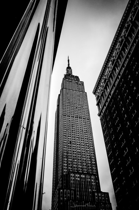 Travel Images Empire State Building seen betwen shiny and textured buildings